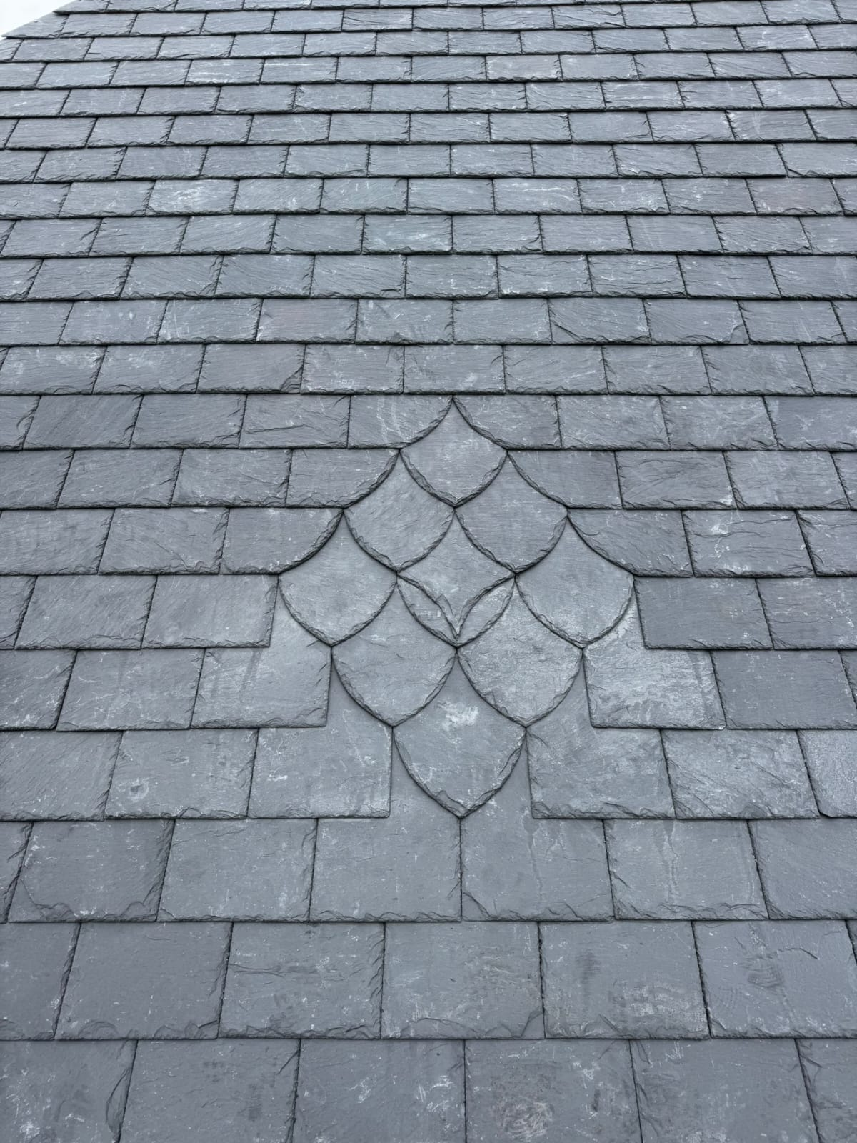 Close-up of a natural slate roof with decorative fish-scale slate detail — Rossi Roofing project